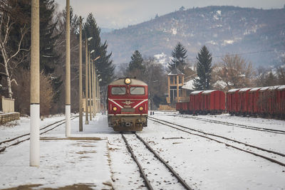 Train on snow covered railroad track against mountain