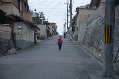 Rear view of man walking on street amidst buildings