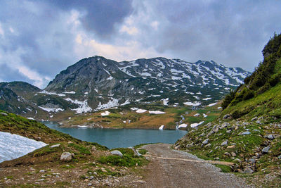 Scenic view of lake by snowcapped mountains against sky