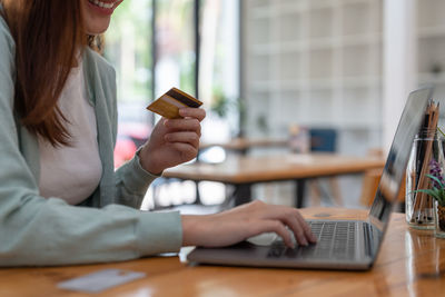 Midsection of woman using mobile phone at table