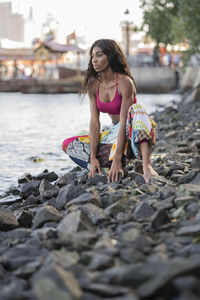 Full length of young woman crouching on rock