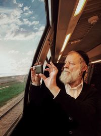 Portrait of man photographing through airplane window