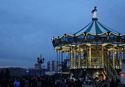 People at amusement park against sky