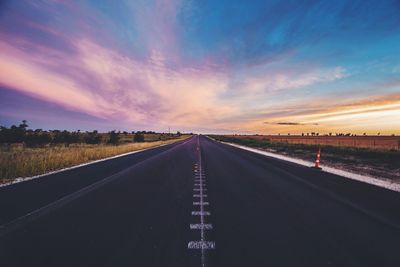 Empty road on field against sky during sunset