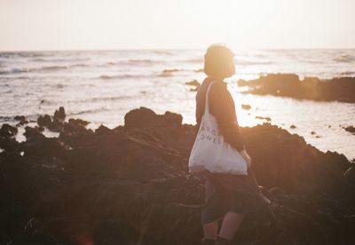 Rear view of woman on beach at sunset