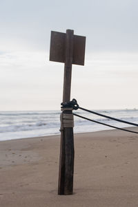 Close-up of cross on beach against sky