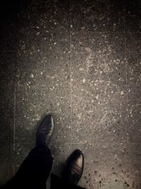 Low section of man standing on tiled floor