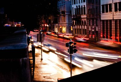 Blurred image of illuminated traffic on city street against buildings at night