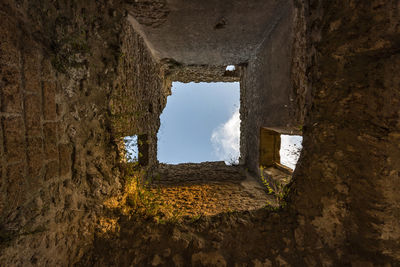 Old ruin building seen through hole in wall