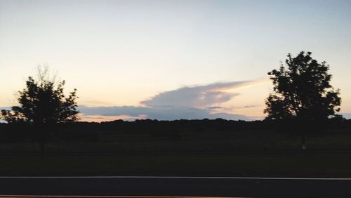 Silhouette trees on landscape against sky at sunset