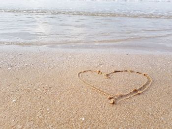 Drawing a heart on sandy beach