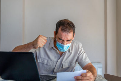 Frustrated man wearing flu mask sitting at office