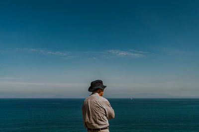 Rear view of man looking at sea against sky