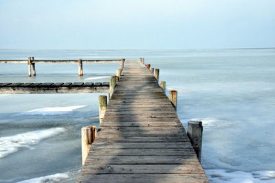 Wooden pier on sea against clear sky