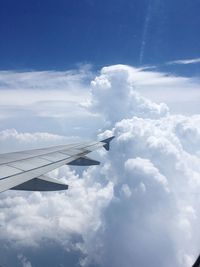 Airplane flying over clouds against blue sky