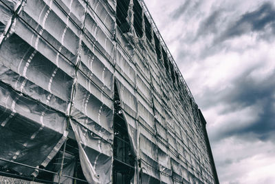 Low angle view of incomplete building against cloudy sky