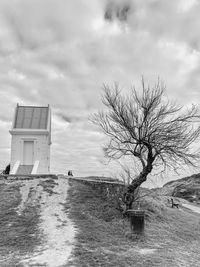 Bare tree by building against sky