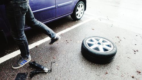 Low section of man standing by car on street