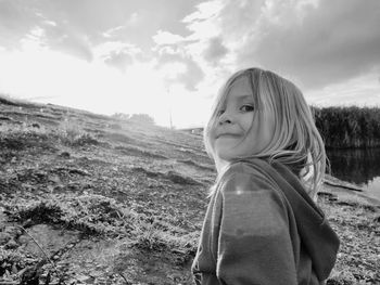 Portrait of girl standing on field against sky