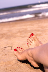 Low section of woman relaxing on sand at beach