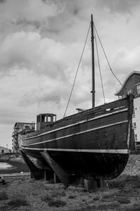 Abandoned ship moored on beach against sky