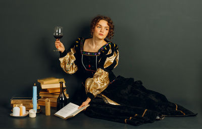 Portrait of young woman holding wineglass against black background