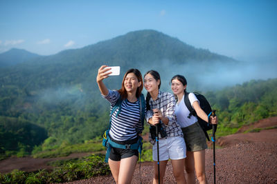 Full length of woman photographing on mountain against sky