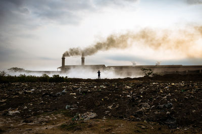 Smoke emitting from factory against sky