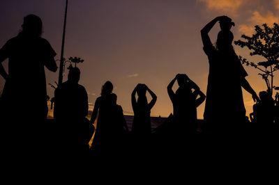 Silhouette of men against sky during sunset