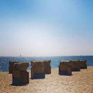 Hooded chairs on beach against clear sky