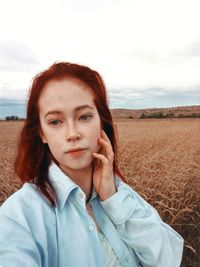 Portrait of young woman lying on land against sky