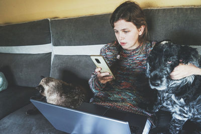 Freelancer with pets using smart phone on sofa
