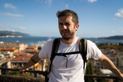 Young man standing in city against sky