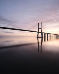 Bridge over sea against sky during sunset