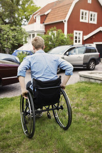 Rear view of man in wheelchair at yard