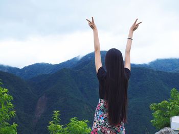 Woman with arms raised against mountains