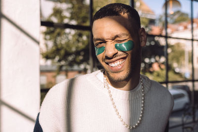 Sunlight shining on smiling man with under-eye patch winking at camera