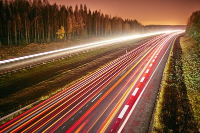 Light trails on road against sky at night