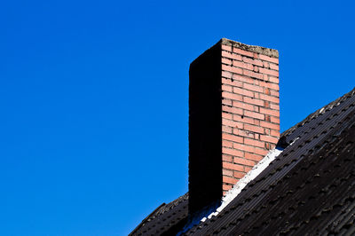 Low angle view of chimney against clear blue sky