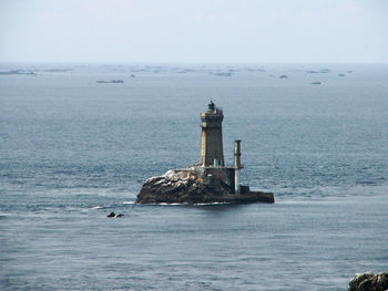 Lighthouse by sea against sky