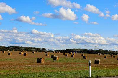 Hay bales on field against sky