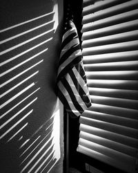 American flag by window blinds, shadows, monochrome image