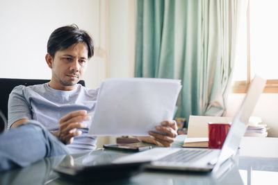 Rear view of man using laptop