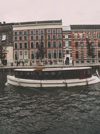 Buildings by canal in city against sky 