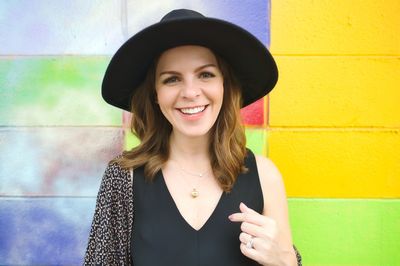 Portrait of smiling young woman standing against wall