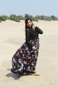 Young woman standing on sand at beach against sky