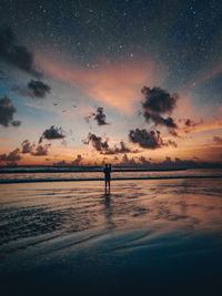 Silhouette man standing on beach against sky during sunset