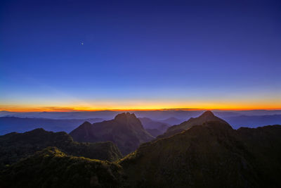 Scenic view of mountains against blue sky at sunset