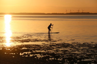 Silhouette man on beach against sky during sunset