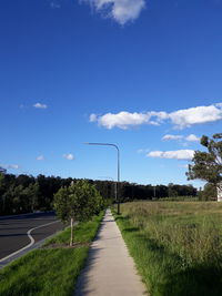 Empty road amidst field against sky